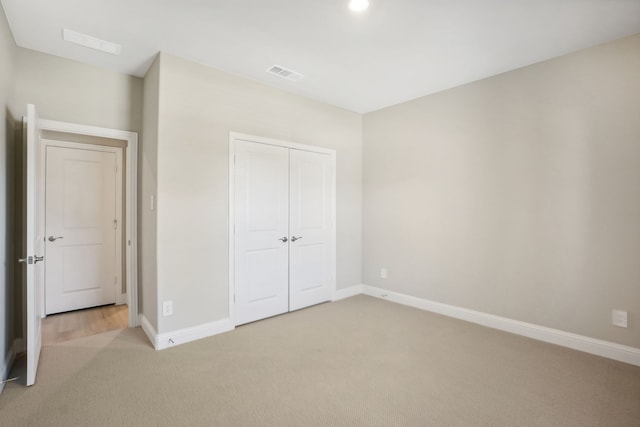 unfurnished bedroom with a closet and light carpet