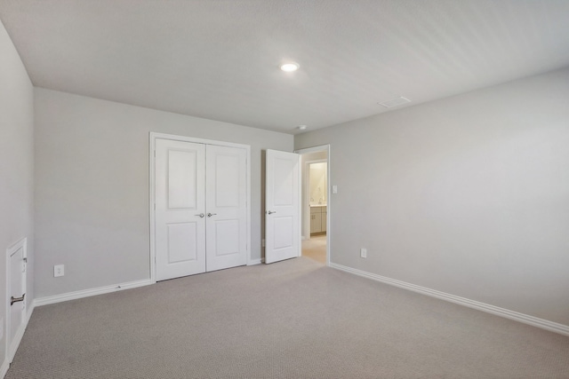 unfurnished bedroom featuring a closet and light colored carpet