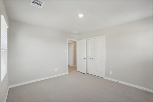 unfurnished bedroom featuring multiple windows, a closet, and light colored carpet