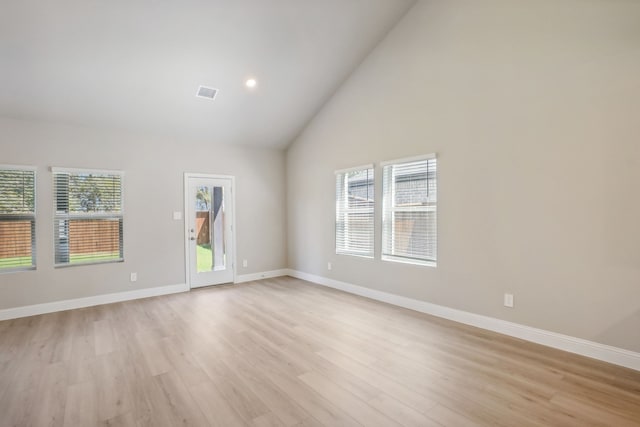 empty room with light hardwood / wood-style flooring and high vaulted ceiling