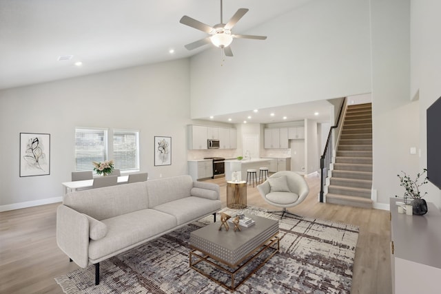 living room featuring high vaulted ceiling, light wood-type flooring, and ceiling fan