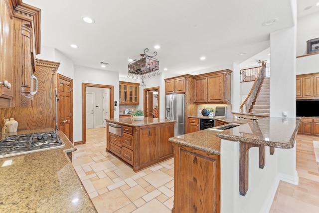 kitchen with light stone counters, stainless steel fridge with ice dispenser, a kitchen breakfast bar, and a center island