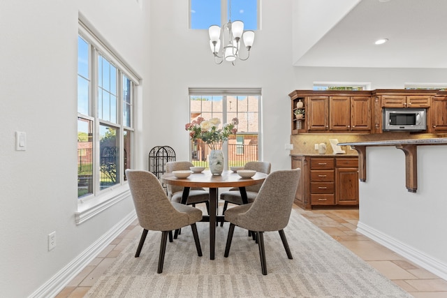 dining space with light tile patterned floors, a chandelier, and a high ceiling