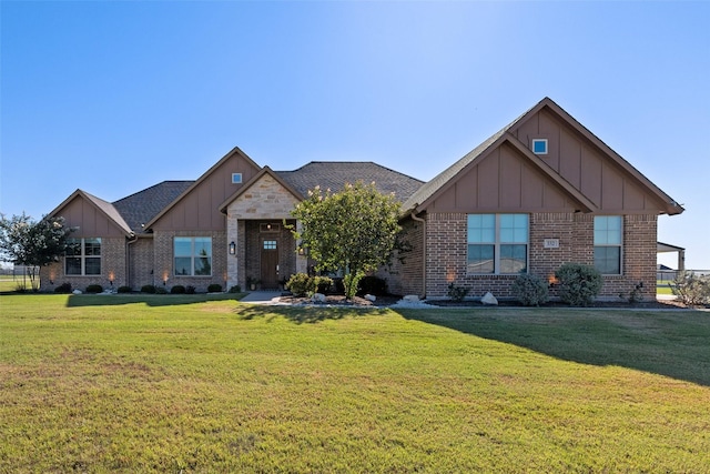 view of front facade with brick siding, board and batten siding, a front lawn, and roof with shingles