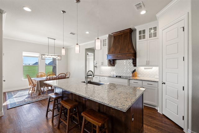 kitchen featuring premium range hood, hanging light fixtures, dark hardwood / wood-style floors, and sink