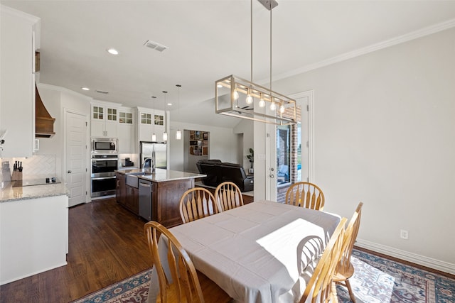 dining area featuring ornamental molding, sink, and dark hardwood / wood-style flooring