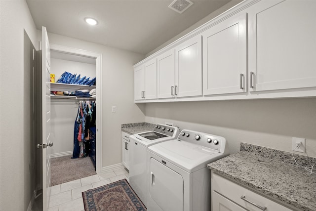 laundry room with washer and dryer, cabinets, and light tile patterned flooring