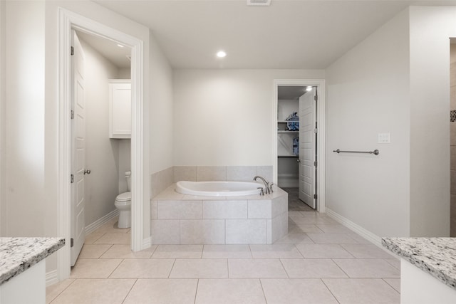 bathroom with vanity, toilet, a relaxing tiled tub, and tile patterned floors