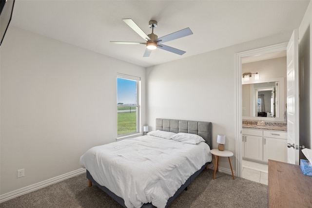 bedroom with light colored carpet, ceiling fan, sink, and connected bathroom