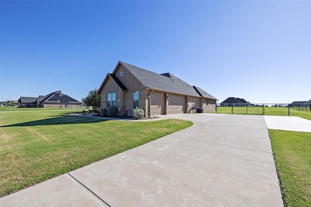 view of side of property with a lawn, driveway, fence, board and batten siding, and brick siding