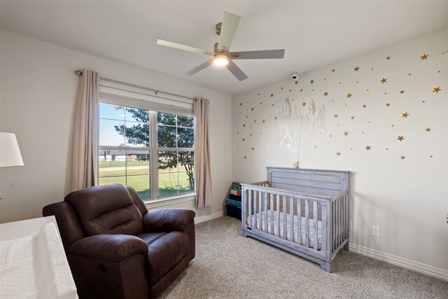 bedroom featuring light carpet, a nursery area, and ceiling fan