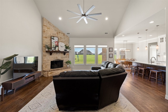 living room featuring a fireplace, dark hardwood / wood-style flooring, high vaulted ceiling, and ceiling fan