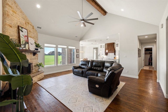 living room featuring high vaulted ceiling, a stone fireplace, dark wood-type flooring, ceiling fan, and beam ceiling