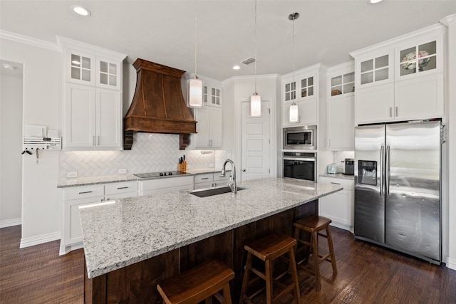 kitchen with a kitchen island with sink, custom exhaust hood, stainless steel appliances, dark hardwood / wood-style flooring, and sink