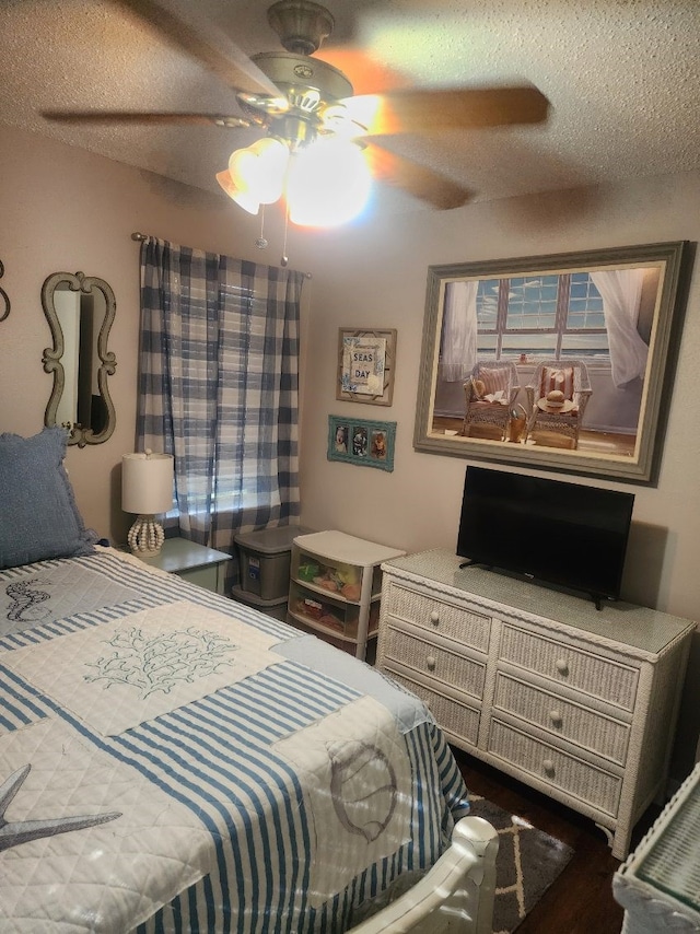 bedroom with a textured ceiling, dark wood-type flooring, and ceiling fan