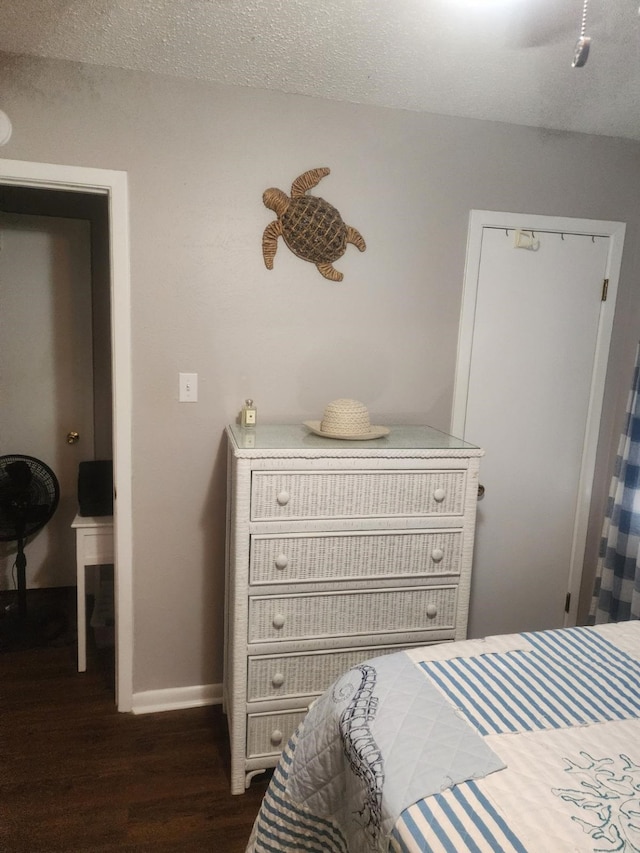 bedroom with a textured ceiling and dark wood-type flooring