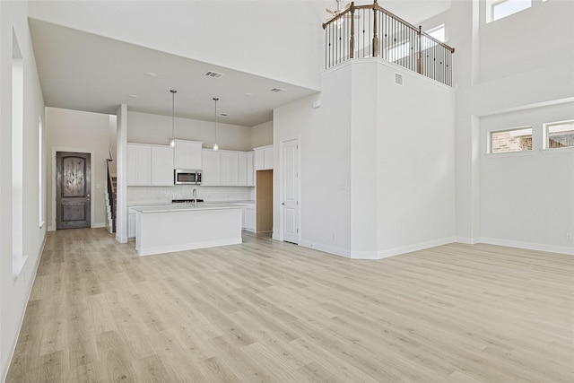 unfurnished living room with a towering ceiling and light hardwood / wood-style flooring