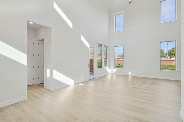 unfurnished living room featuring a towering ceiling and light hardwood / wood-style flooring