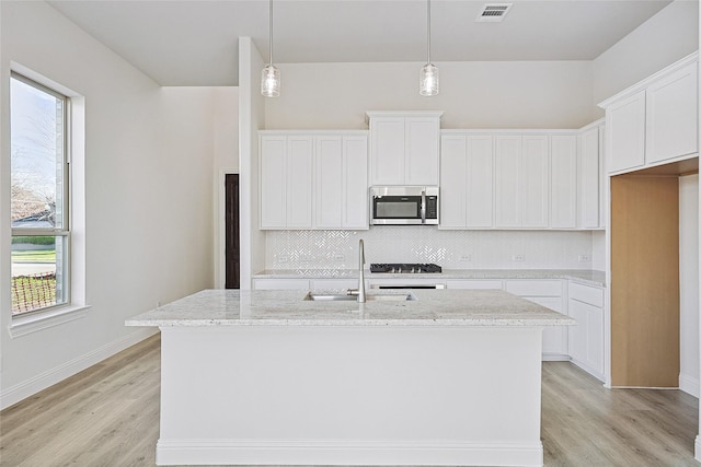 kitchen featuring a center island with sink, white cabinetry, and sink