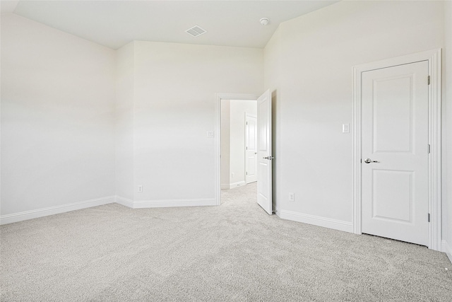 carpeted empty room with vaulted ceiling