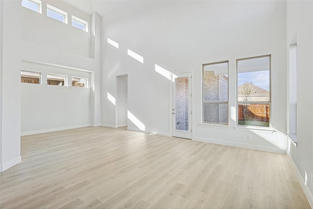 unfurnished living room with light hardwood / wood-style flooring and a high ceiling