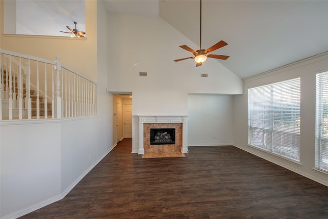 unfurnished living room with dark hardwood / wood-style flooring, a tiled fireplace, high vaulted ceiling, and ceiling fan