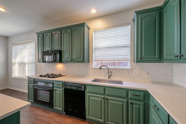 kitchen with black appliances, dark hardwood / wood-style floors, green cabinetry, and sink