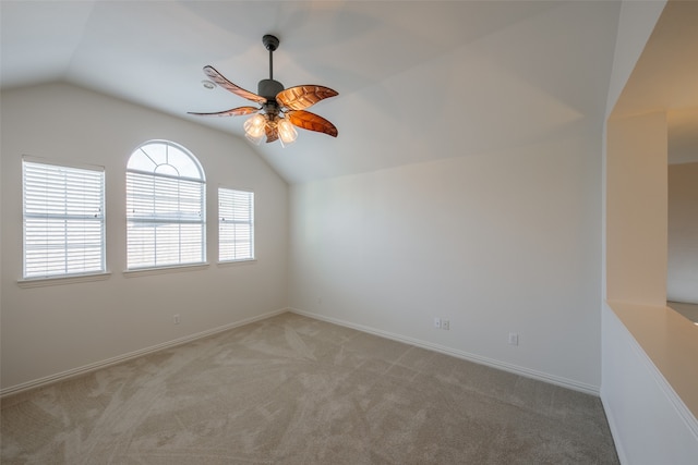 carpeted spare room featuring vaulted ceiling and ceiling fan