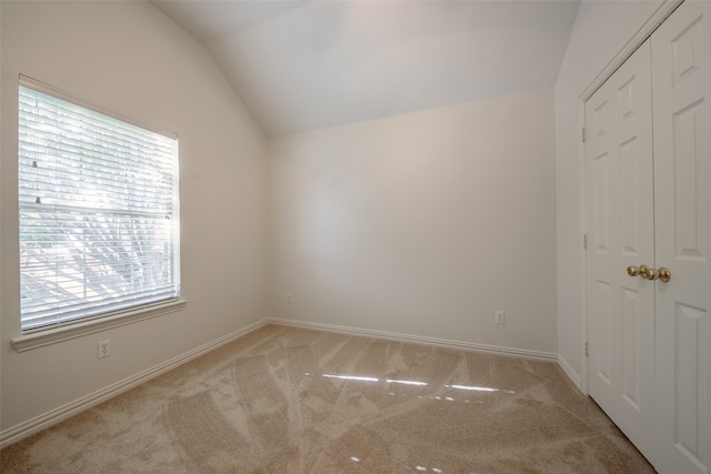 carpeted spare room with vaulted ceiling