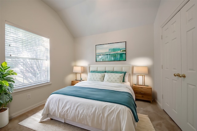 bedroom featuring lofted ceiling, a closet, and light carpet