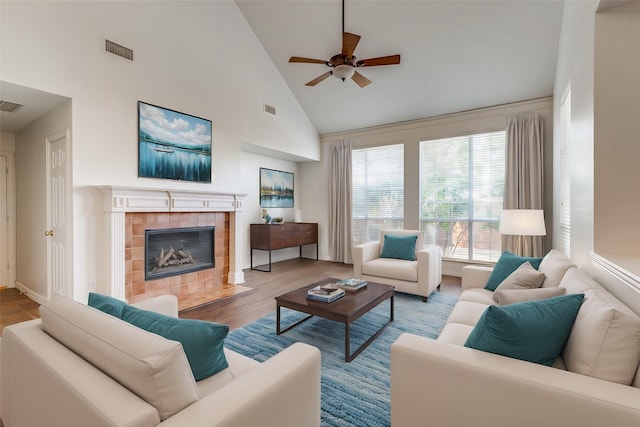 living room with ceiling fan, light wood-type flooring, high vaulted ceiling, and a fireplace