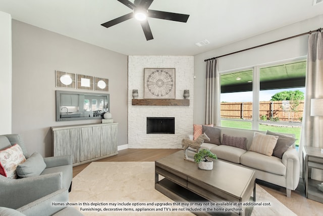 living room featuring light hardwood / wood-style floors, a fireplace, and ceiling fan