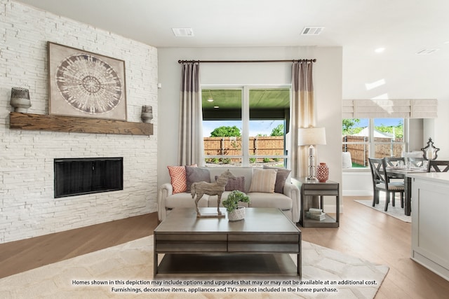 living room with a stone fireplace and light wood-type flooring