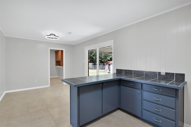 kitchen with kitchen peninsula, crown molding, light tile patterned floors, and blue cabinets