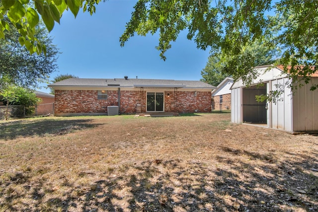 rear view of house with cooling unit, a shed, and a yard