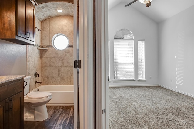 full bathroom featuring tiled shower / bath, lofted ceiling, toilet, vanity, and hardwood / wood-style flooring