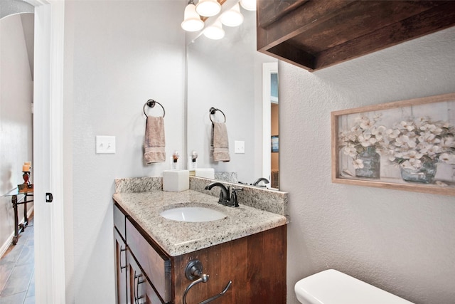 bathroom with beamed ceiling, vanity, and toilet