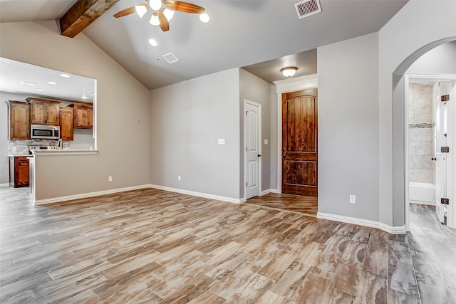 unfurnished living room featuring vaulted ceiling with beams, ceiling fan, and light wood-type flooring