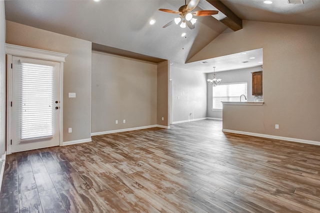 unfurnished living room with sink, lofted ceiling with beams, ceiling fan with notable chandelier, and light wood-type flooring