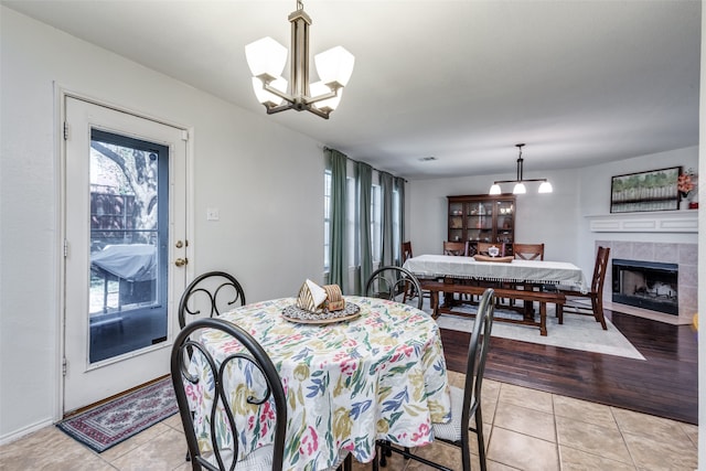 dining space with a chandelier, a tile fireplace, and light hardwood / wood-style floors