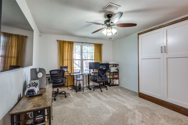 carpeted office with a textured ceiling and ceiling fan