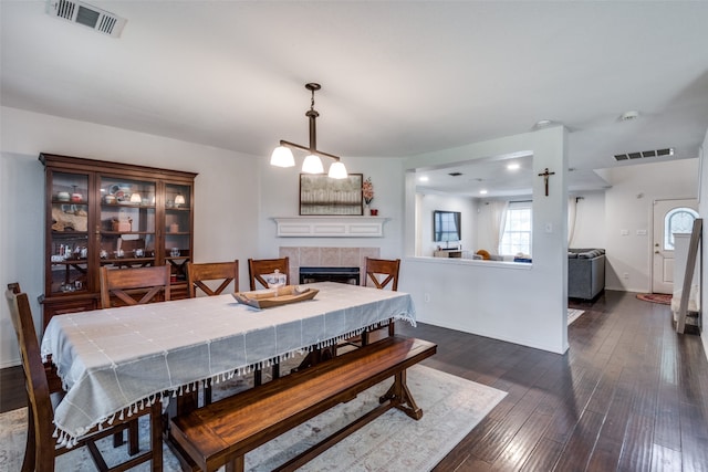 dining space featuring dark wood-type flooring and a tile fireplace