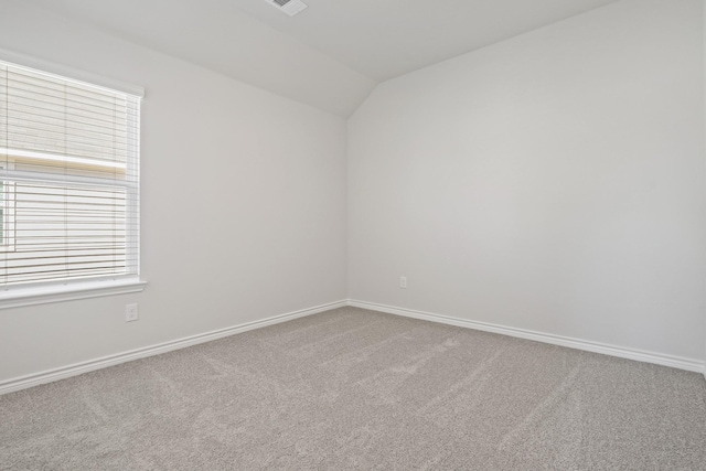 carpeted spare room with visible vents, vaulted ceiling, and baseboards