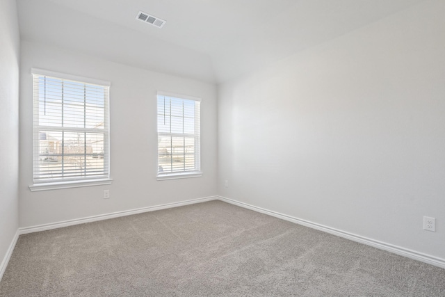 carpeted empty room featuring lofted ceiling, visible vents, and baseboards