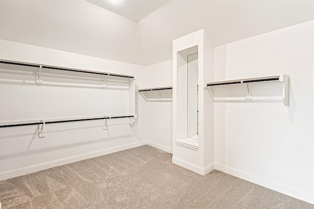 spacious closet featuring light colored carpet and lofted ceiling