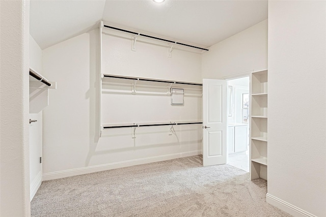 walk in closet with light carpet and vaulted ceiling