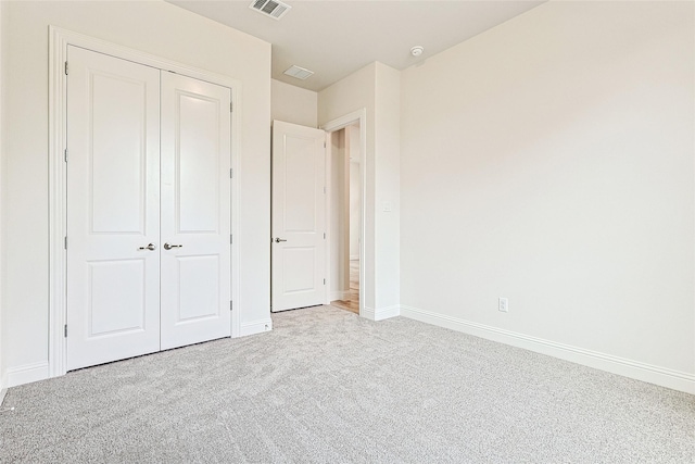 unfurnished bedroom with a closet and light colored carpet