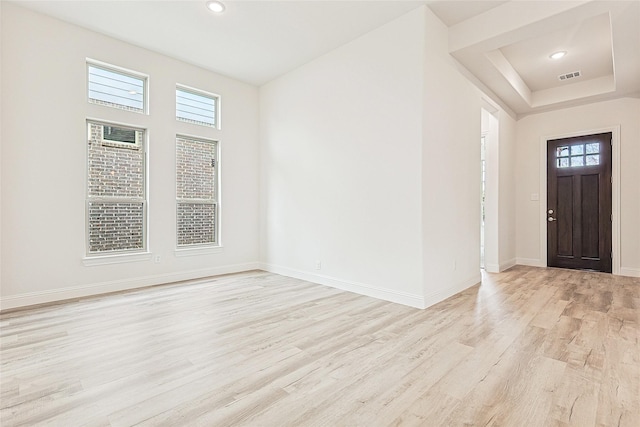 entryway featuring a raised ceiling and light hardwood / wood-style flooring