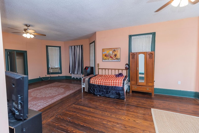 bedroom with a textured ceiling, cooling unit, ceiling fan, and dark hardwood / wood-style flooring