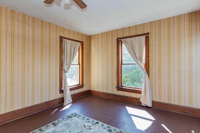 unfurnished room featuring a healthy amount of sunlight, ceiling fan, and dark hardwood / wood-style floors